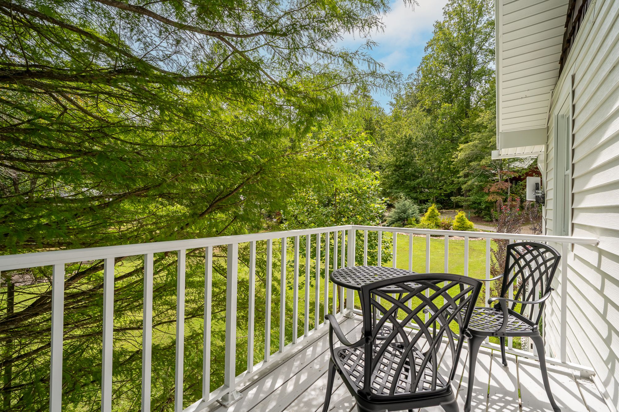 The private balcony off the Patriot room, with a bistro table and two chairs over the lawn